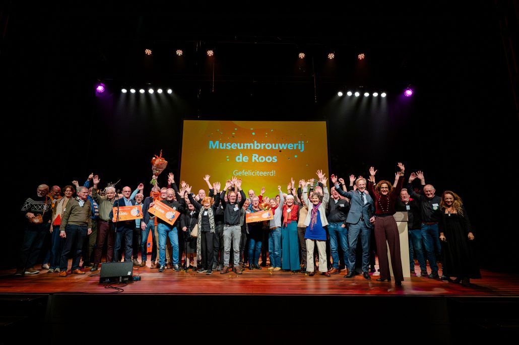 De winnaars van 2023 nemen de prijs in ontvangst op een podium.