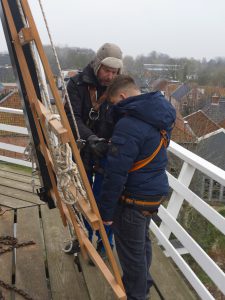 Twee mensen die iets bekijken op de wiek van een molen