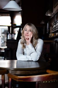 Dichter Irene Wiersma aan een tafeltje in een bruine kroeg. Foto: Nienke Maat.