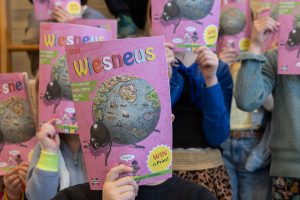 Kinderen houden het tijdschrift Wiesneus voor hun gezicht.