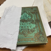 Een koperen plakkaat, met groene roest, deels verpakt in papier