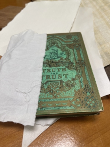 Een koperen plakkaat, met groene roest, deels verpakt in papier